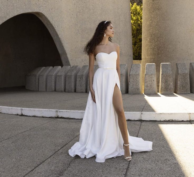 a woman in a white dress is standing outside