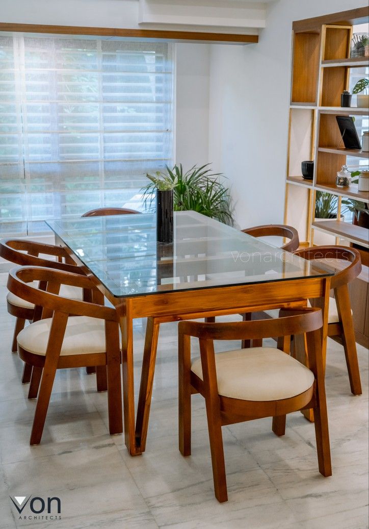 a glass table with chairs around it in front of a bookshelf and shelves