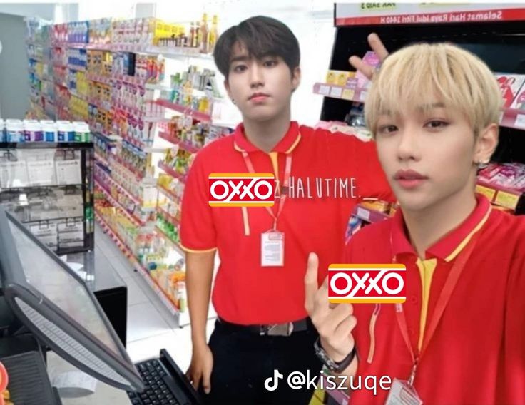 two young men in red shirts standing next to each other near a computer monitor and keyboard