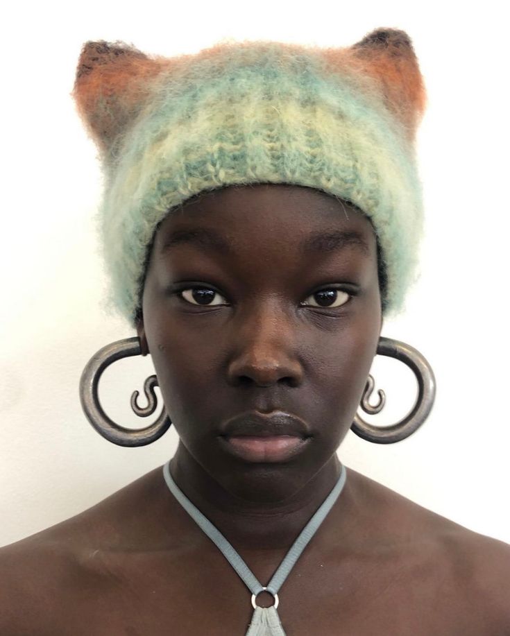 a woman wearing a cat earring and a green knitted hat on top of her head