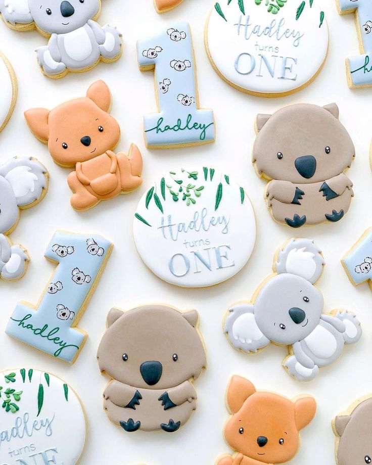 cookies decorated with baby's first birthday designs and teddy bears are arranged on a table