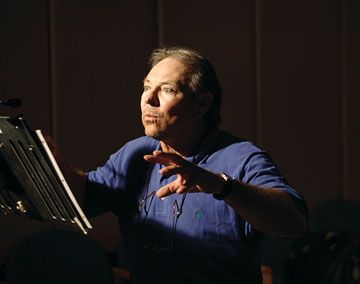 a man standing in front of a laptop computer holding his hands out to the side