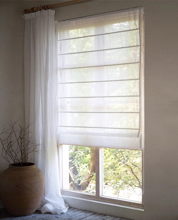 a window with white sheer curtains and a potted plant