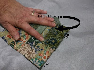 a person's hand on top of a piece of fabric with the needle pointing towards it