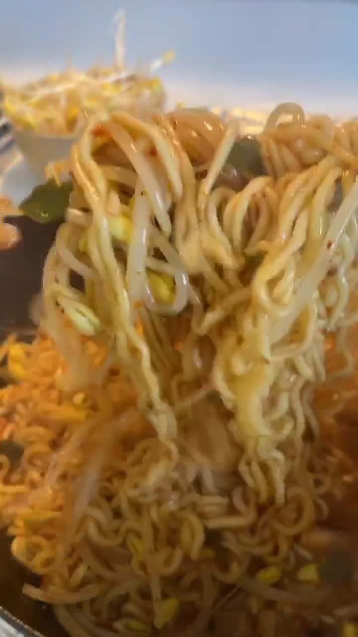 noodles being cooked in a pan with vegetables and sauce on the side, ready to be eaten