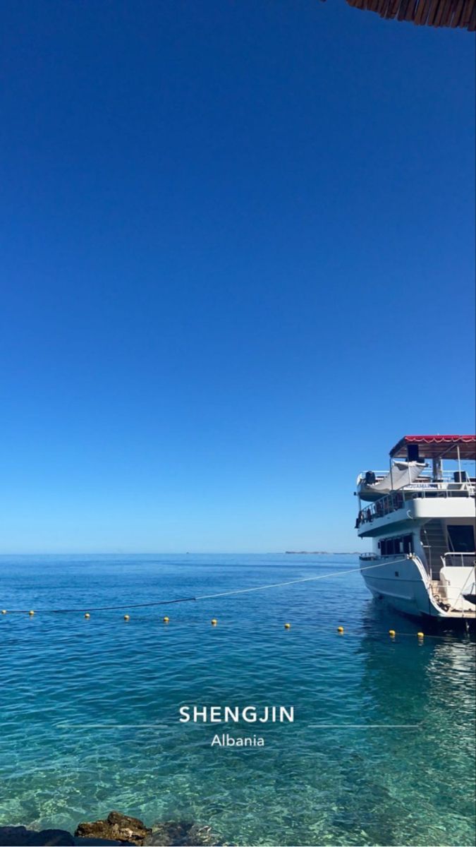 a large boat floating on top of the ocean next to a shore line with people in it