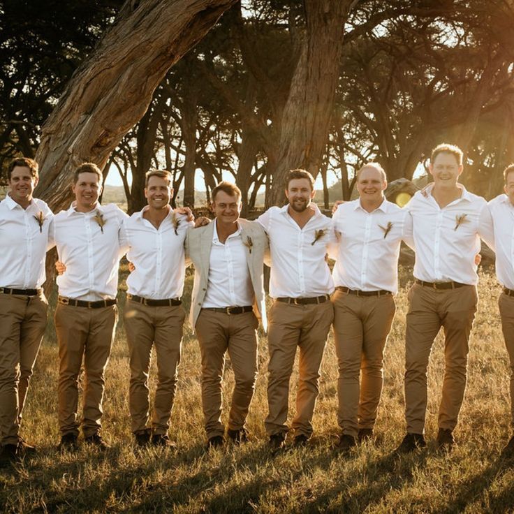 a group of men standing next to each other on top of a grass covered field