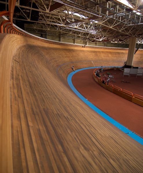 a person riding a skateboard on an indoor track in a building with wooden flooring