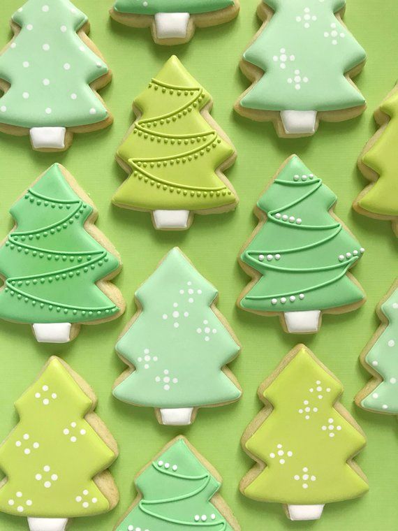 christmas cookies decorated with green and white icing on a green tablecloth covered in trees