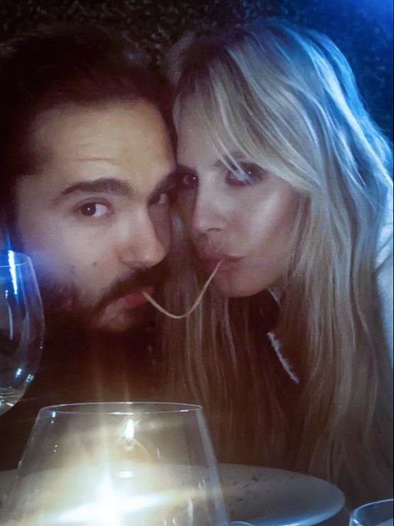 a man and woman are posing for a photo in front of a glass of wine