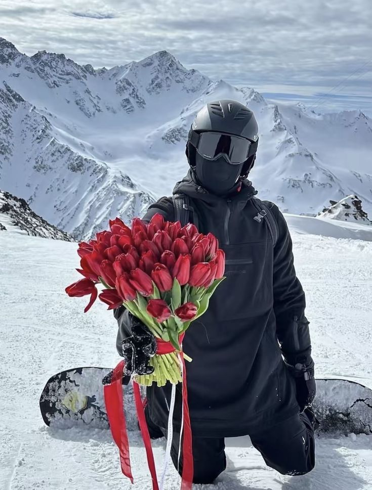 a snowboarder sitting in the snow with red flowers