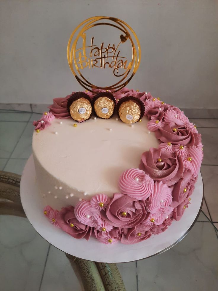 a birthday cake with pink flowers and gold decorations