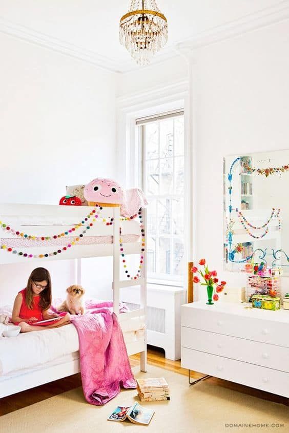 a woman sitting on top of a white bunk bed next to a pink pony toy