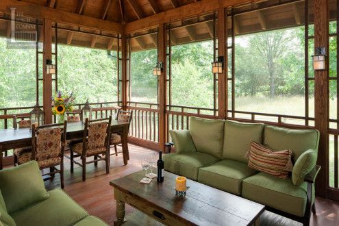 a living room filled with green furniture and lots of wooden windows covered in wood planks