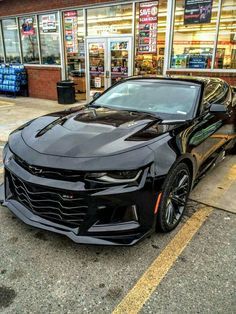 a black chevrolet camaro parked in front of a store