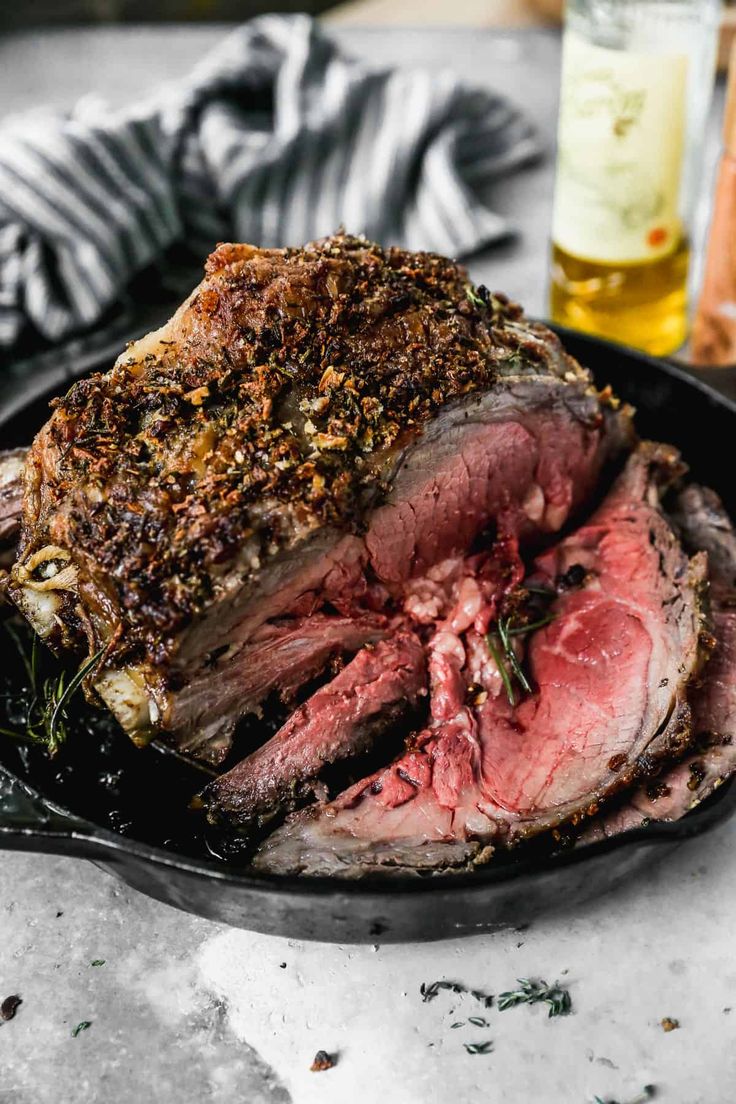 a roasting pan with meat and herbs on it