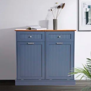 a blue cabinet with two drawers and a plant in the corner next to it on top of a hard wood floor