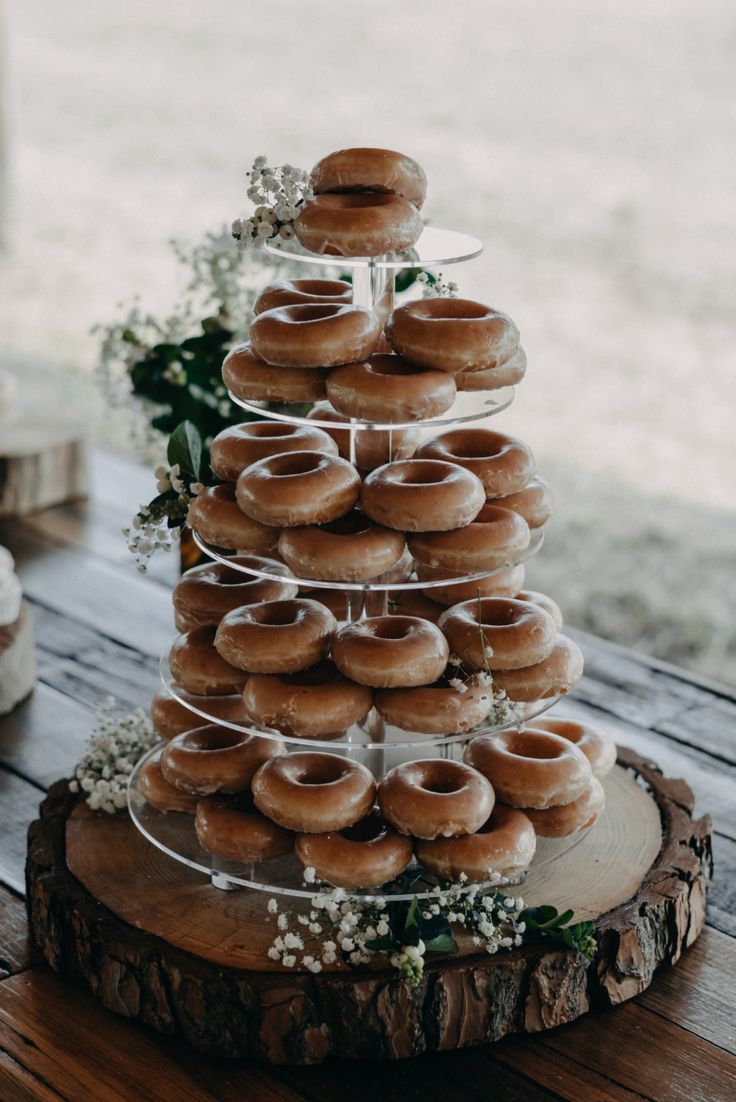 a wooden table topped with a tiered cake covered in donuts