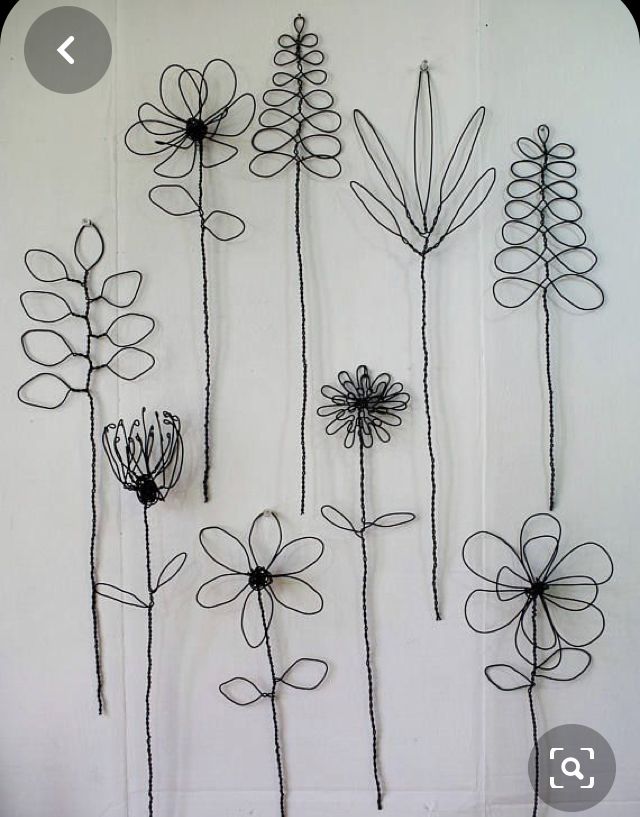 four metal flowers are hanging on the wall