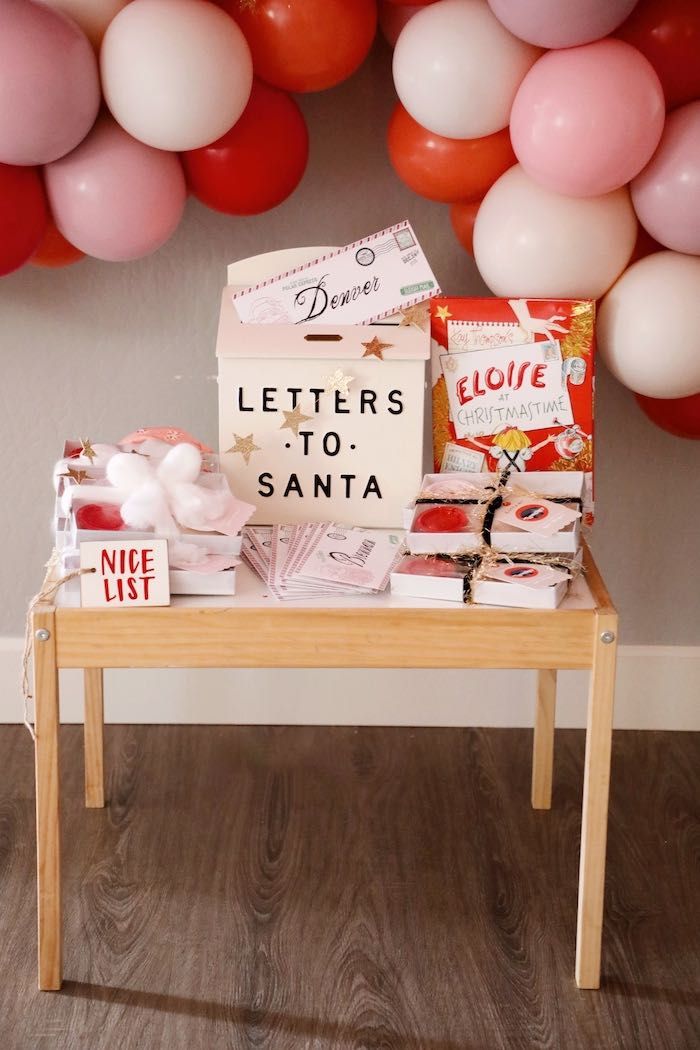 a wooden table topped with lots of boxes filled with candy next to balloon garlands