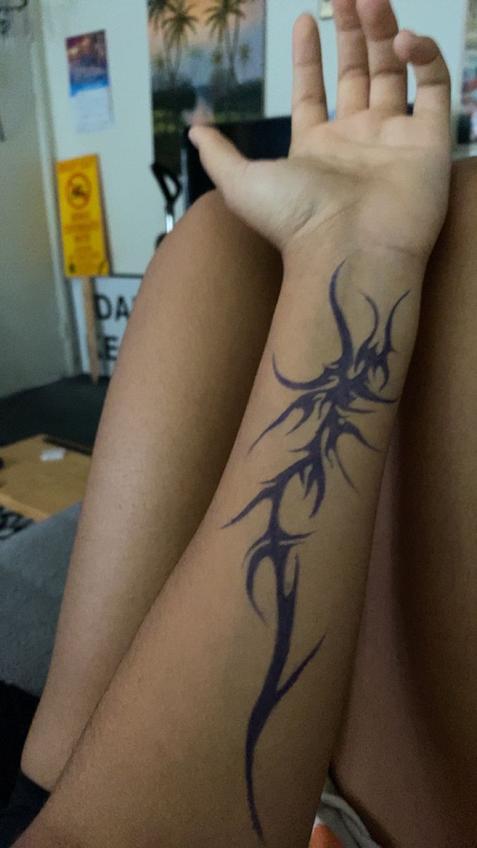 a woman with a tattoo on her arm sitting in front of a computer desk and looking at the camera