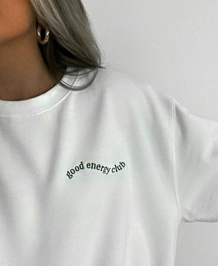 a woman wearing a white t - shirt with the words good energy club on it