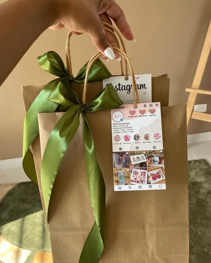 a person holding a brown paper bag with a green ribbon and tag attached to it