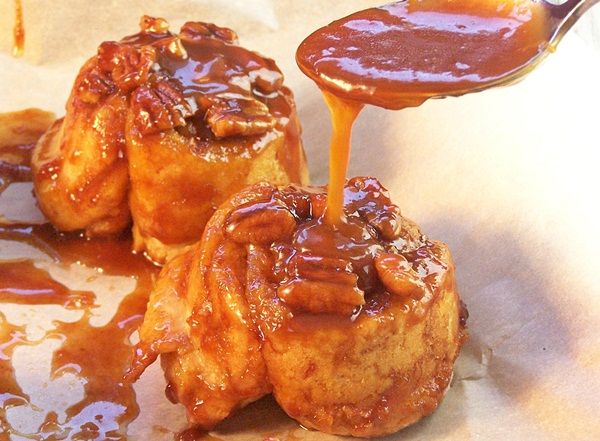 some kind of cinnamon buns with caramel sauce being drizzled on them