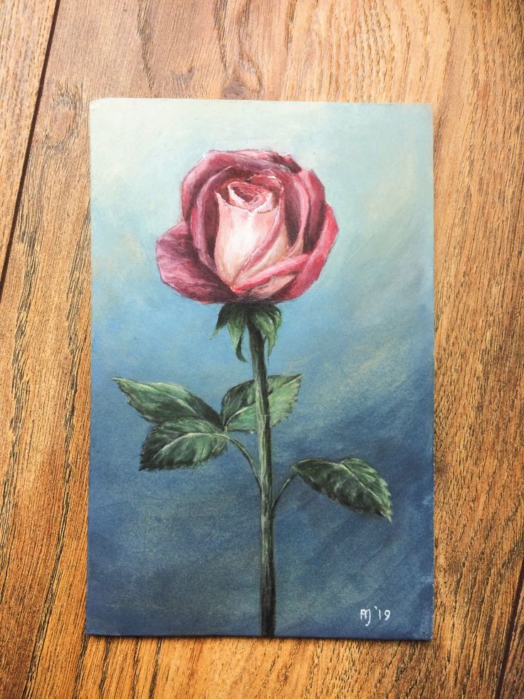 a painting of a pink rose on a wooden table