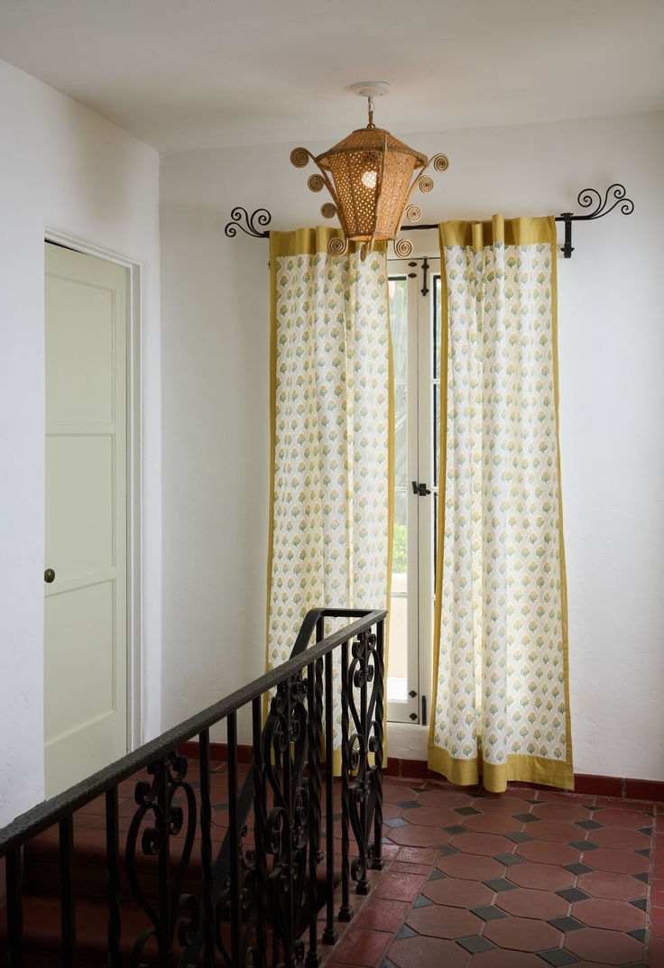 a balcony with curtains and a chandelier hanging from the ceiling, next to a door