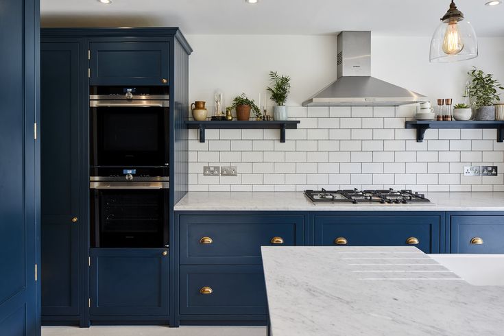 a kitchen with blue cabinets and marble counter tops, white subway tile backsplash