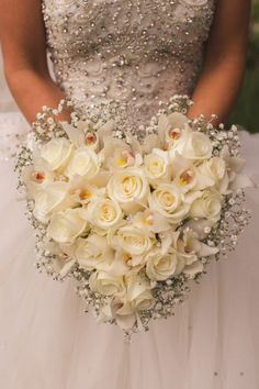 a bride holding a bouquet of white roses