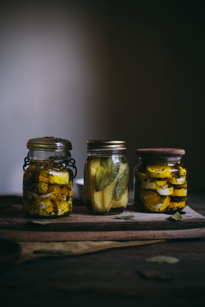 three jars filled with pickles sitting on top of a wooden table