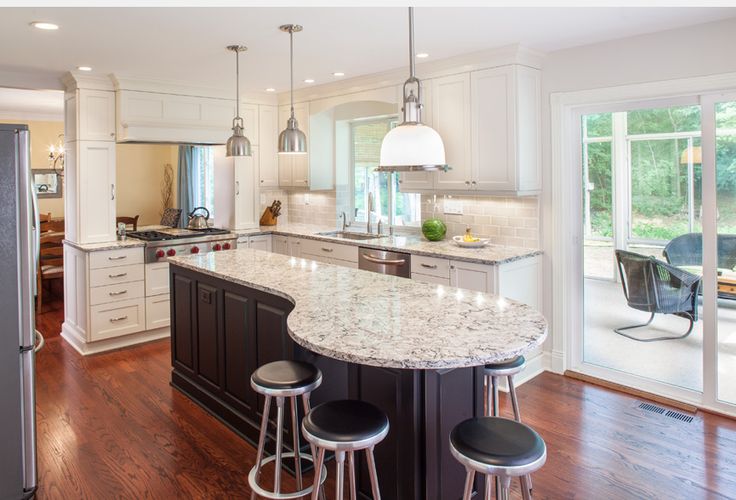 a large kitchen with an island in the middle and two stools at the end