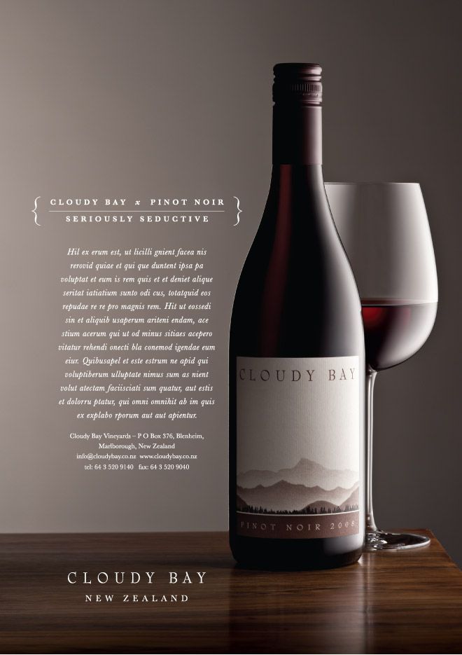 a bottle of wine next to a glass on top of a wooden table with the label cloudy bay