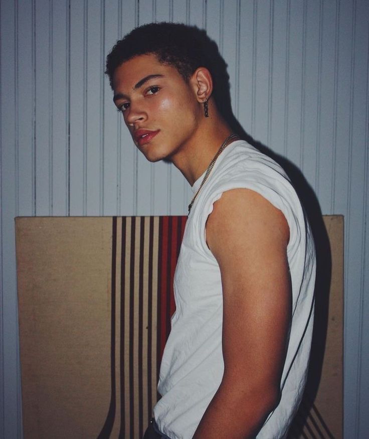 a young man standing in front of a striped wall