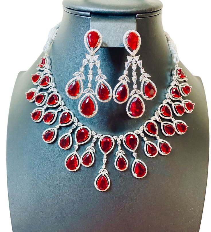 Enhance your jewelry collection with our CZ American Diamond and Red Stone Necklace set. This elegant set is perfect for any party or special occasion. The combination of CZ diamonds and red stones adds a touch of sophistication and glamour. Up your style game and stand out from the crowd with this stunning necklace set. Jewellery Care- Keep the jewellery dry, avoid contact with perfumes and water. Ruby Necklaces With Sparkling Stones For Party, Party Ruby Necklaces With Sparkling Stones, Red Stone Wedding Necklaces, Party Ruby Necklace With Sparkling Stones, Luxury Red Rhinestone Jewelry, Elegant Red Bridal Necklace With Sparkling Stones, Red Stone Necklaces For Formal Occasions, Red Stone Necklace For Formal Occasions, Red Hand Set Necklace For Party