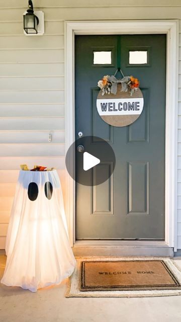 a welcome sign on the front door of a house with a ghost bag in front of it