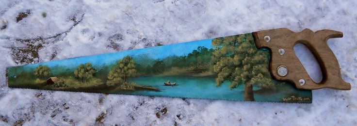 a pair of scissors sitting on top of a snow covered ground next to a painting