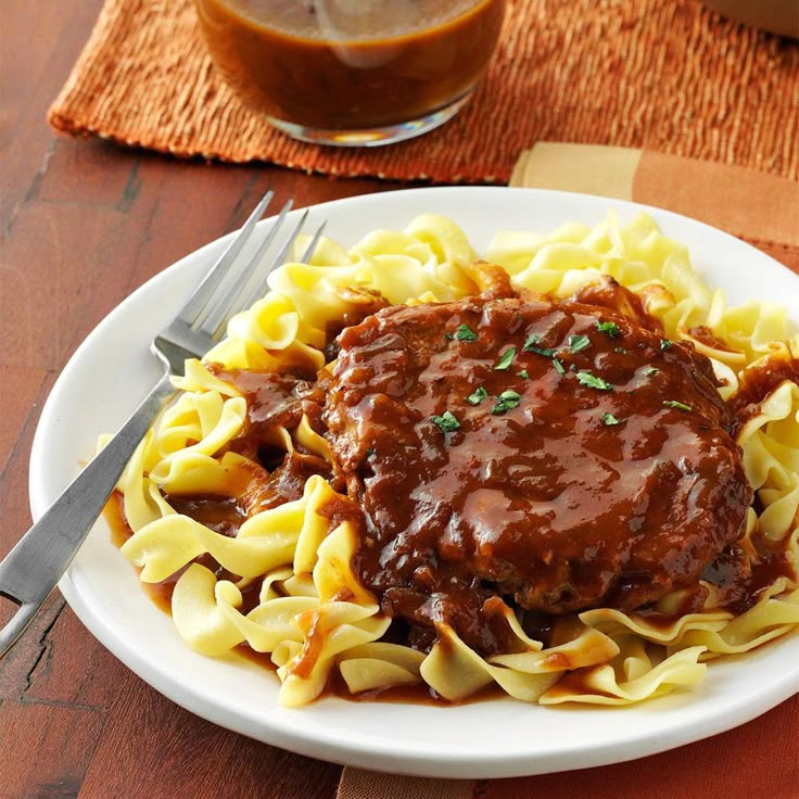 a white plate topped with pasta covered in sauce and gravy next to a fork