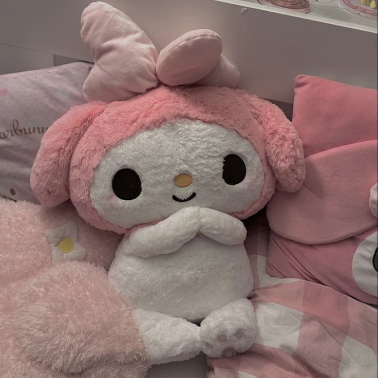 a pink stuffed animal sitting on top of a bed