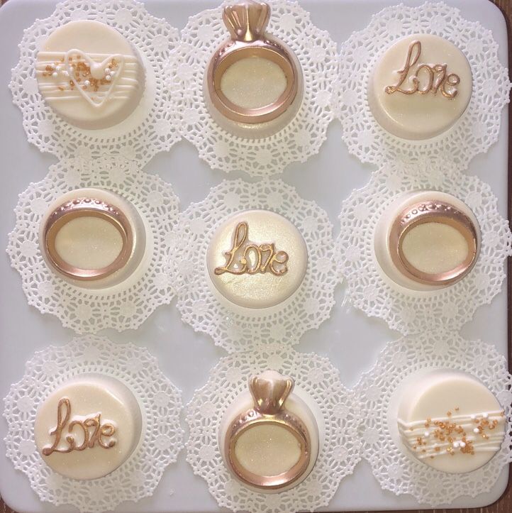 the wedding rings and ring box are decorated with gold lettering on white lace doily