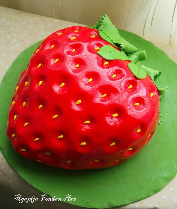 a strawberry shaped cake sitting on top of a green plate