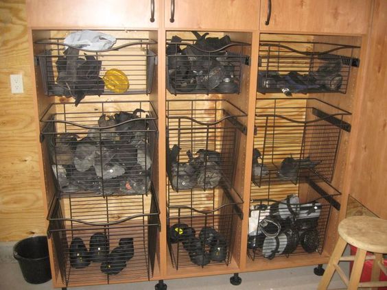 several cages filled with many different types of items in a storage area next to a stool