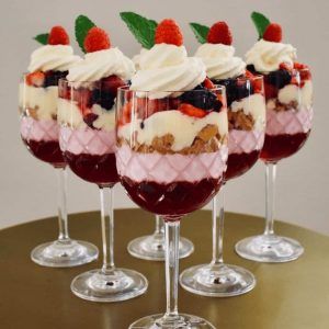 four glasses filled with dessert sitting on top of a table