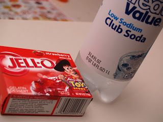 a bottle of jello next to a box of toothpaste on a table