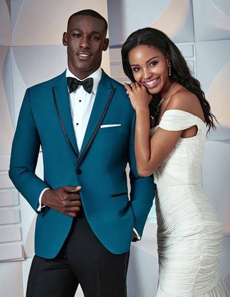 a man in a blue suit and woman in a white dress posing for a photo