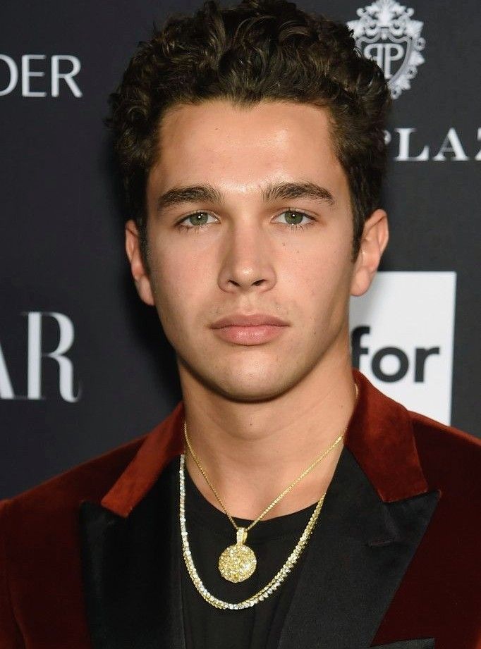 a young man wearing a red velvet suit and gold necklace with a medallion on his neck