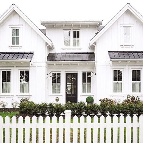 a white picket fence in front of a large house with windows and black shutters