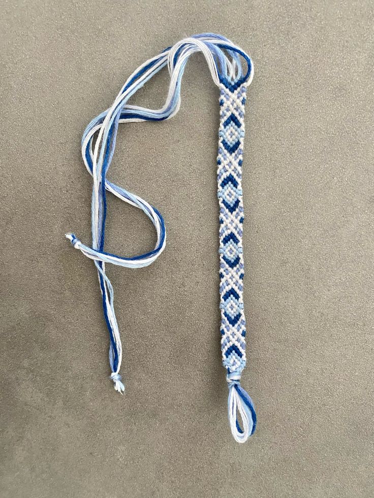 a blue and white lanyard with a knot at the end on a gray surface